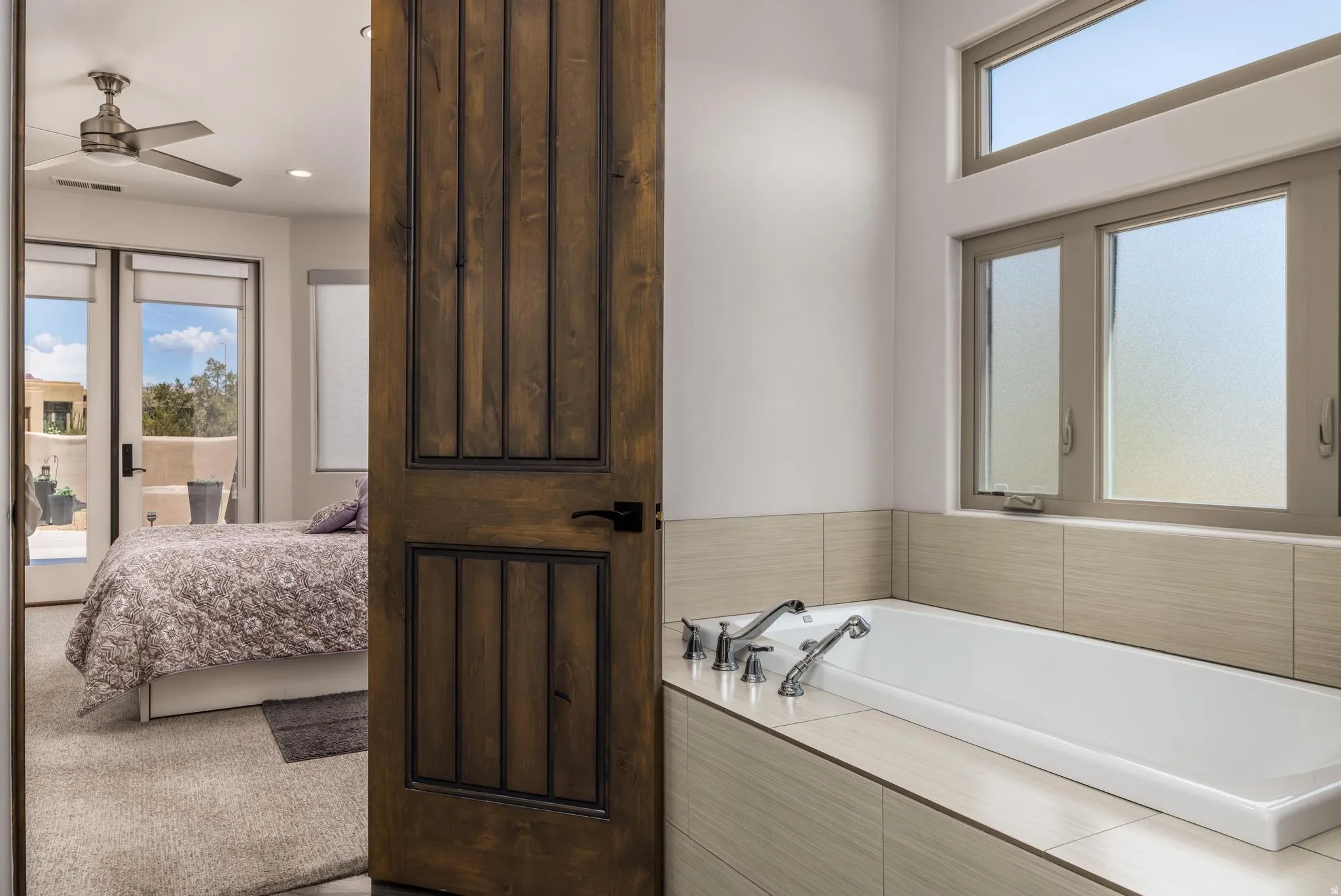 Deep soaking tub with chrome fixtures, surrounded by neutral-toned tile