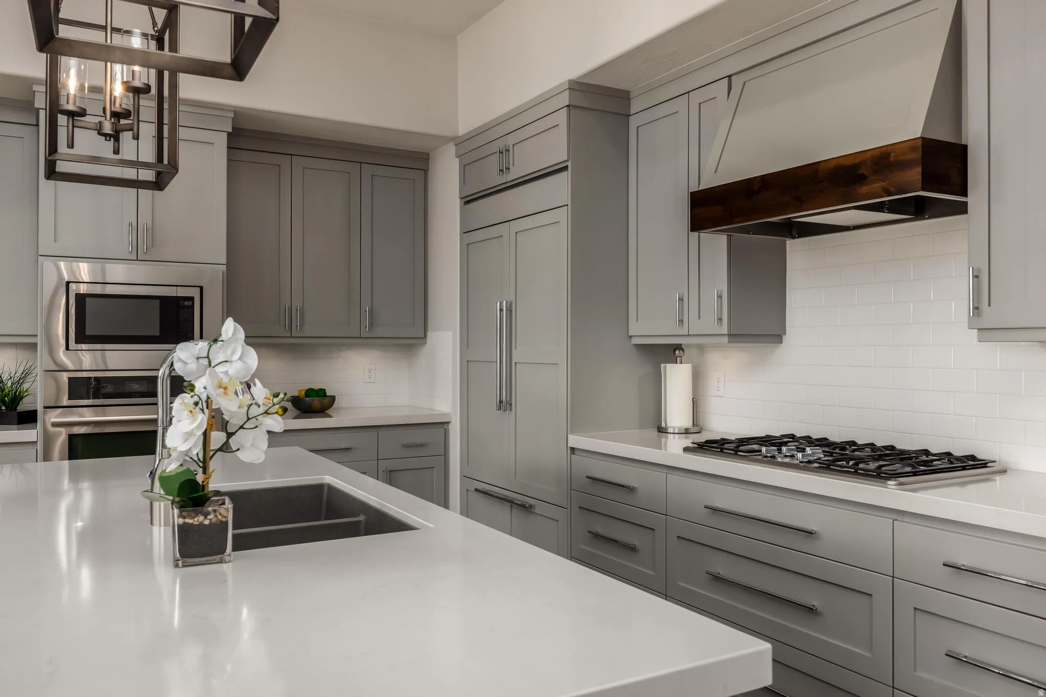 Kitchen featuring grey shaker cabinetry, stainless steel appliances, white subway tile backsplash, and light-toned countertops