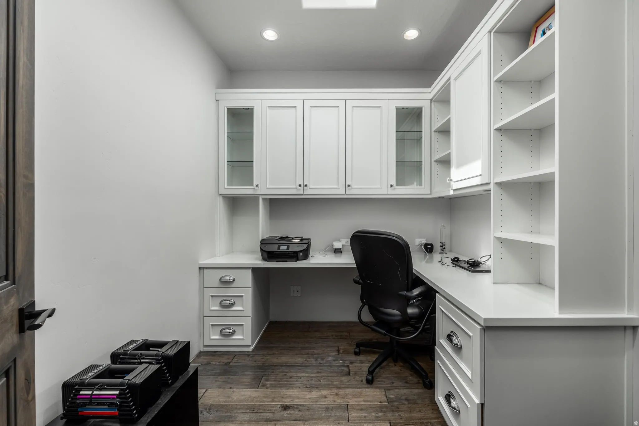 Built-in white cabinetry, integrated desk space, upper glass-front cabinets, and open shelving