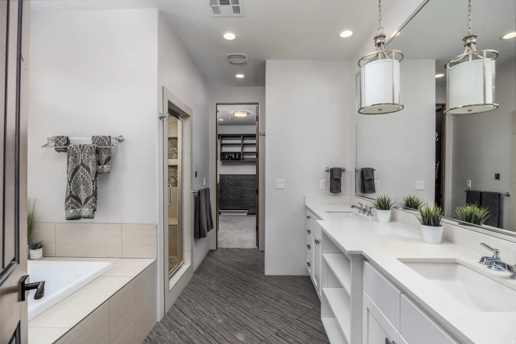 Dual vanity with white cabinetry and integrated sinks, full-width mirror, recessed lighting, and a built-in bathtub. Primary Bathroom
