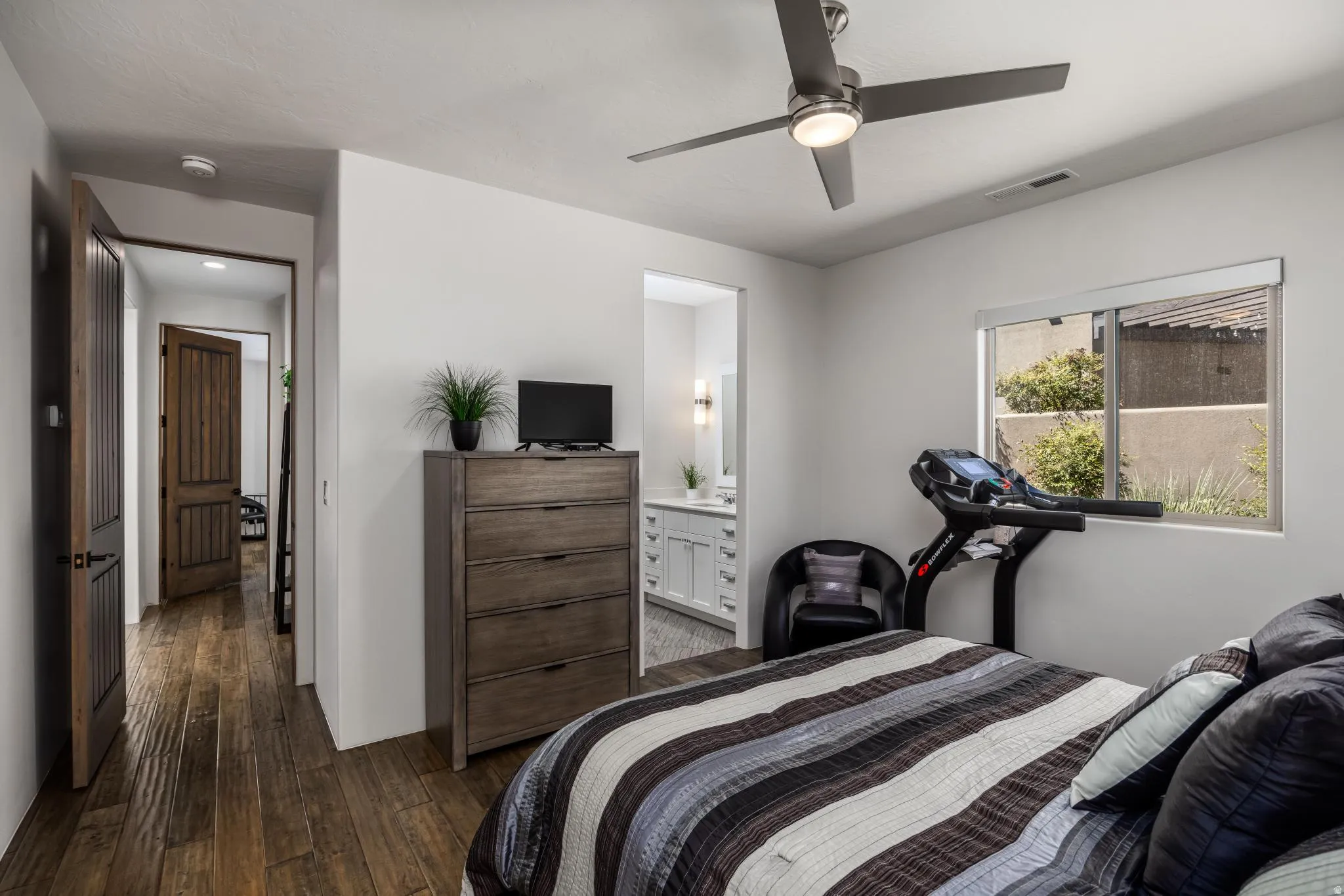 Wood-finish flooring throughout, ceiling fan with integrated lighting, and a window with exterior views