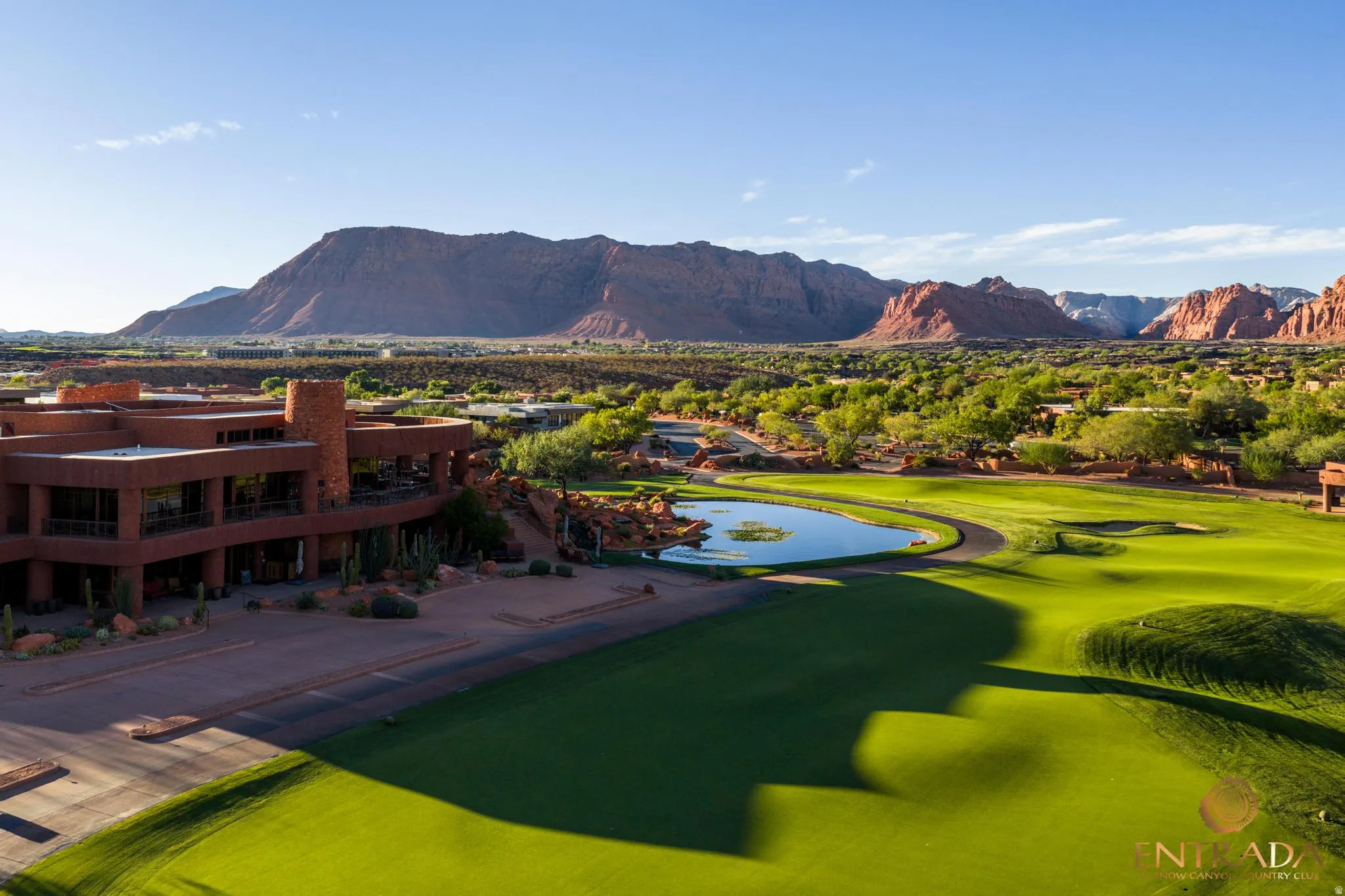 Expansive golf course with manicured greens, a reflective water feature, and a desert mountain backdrop