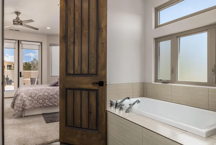 Deep soaking tub with chrome fixtures, surrounded by neutral-toned tile