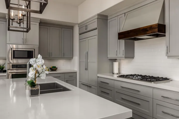 Kitchen featuring grey shaker cabinetry, stainless steel appliances, white subway tile backsplash, and light-toned countertops