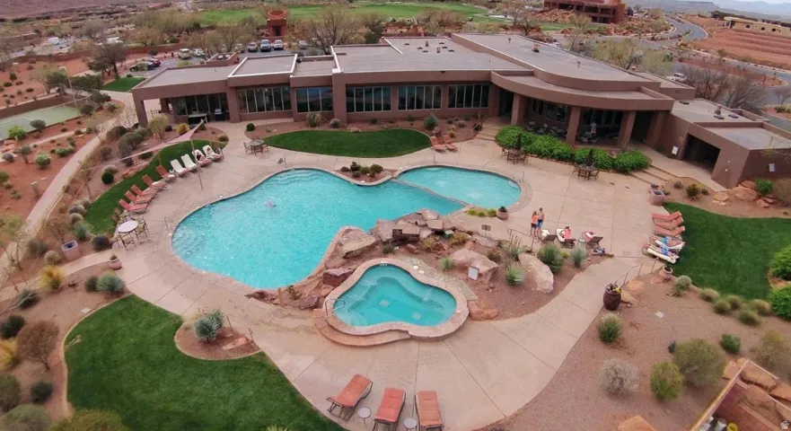 Resort-style pool area featuring two distinct pools, an integrated spa, expansive paver decking, and surrounding landscaped grounds
