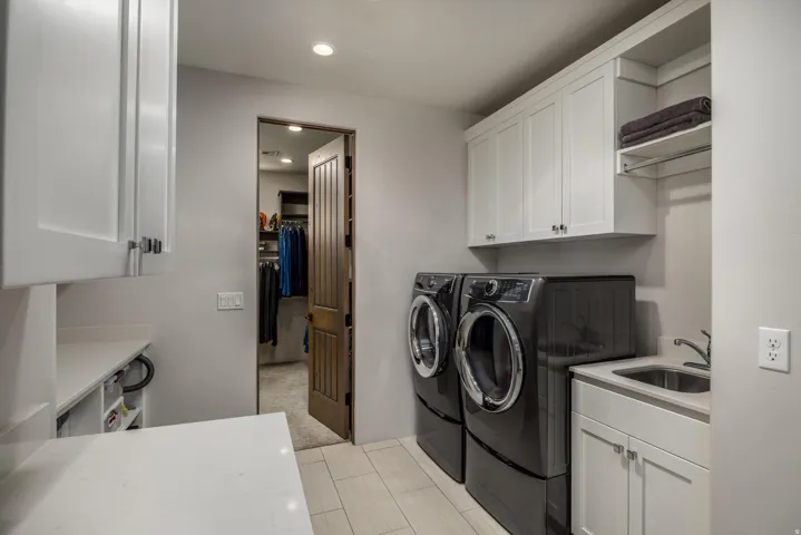 Laundry room featuring white shaker cabinetry, light-toned wood-look flooring, a utility sink with a stainless steel faucet, and recessed lighting