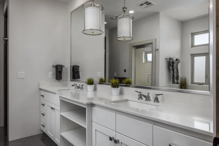 Dual vanity with white cabinetry and integrated sinks, complemented by chrome fixtures. Primary Bathroom