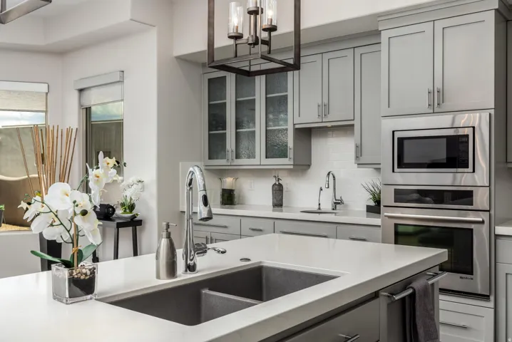 Kitchen featuring a large island with an integrated sink, built-in stainless steel appliances, shaker-style cabinetry, and a subway tile backsplash