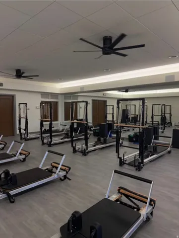 Recessed lighting with a drop ceiling, mirrored wall, multiple ceiling fans, and wood-finish flooring