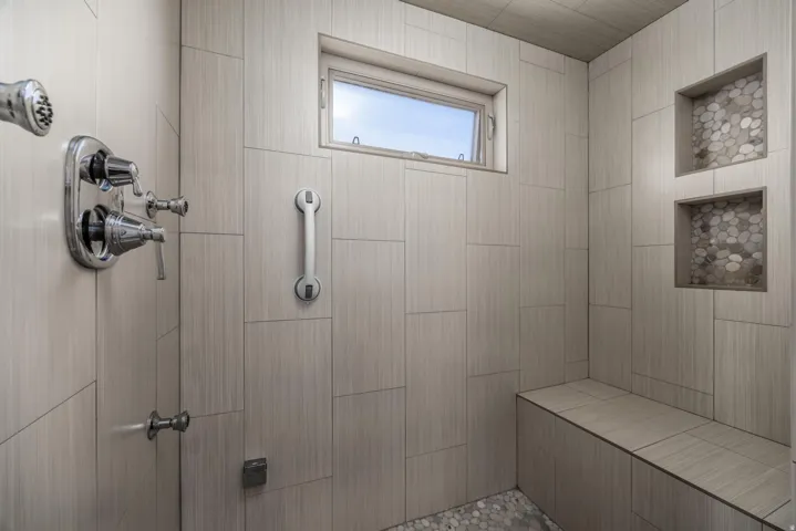 Tiled shower with a built-in bench, two tiled niches, and a window/ Steam Shower Primary Bathroom
