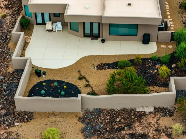 Spacious patio with curved borders, surrounded by desert landscaping and low-profile retaining walls
