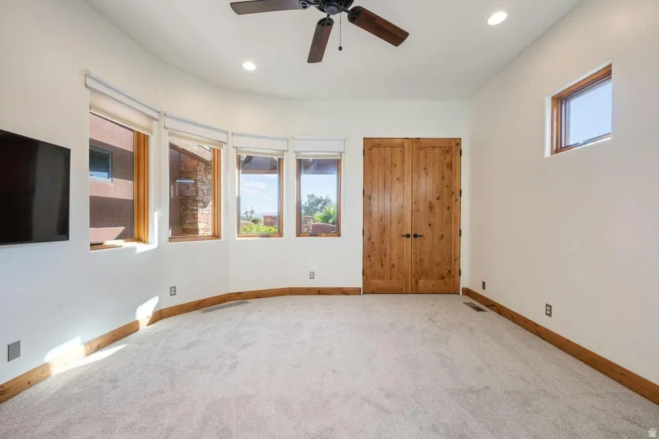 Curved wall with multiple windows, recessed lighting, wood-finish baseboards, and a ceiling fan