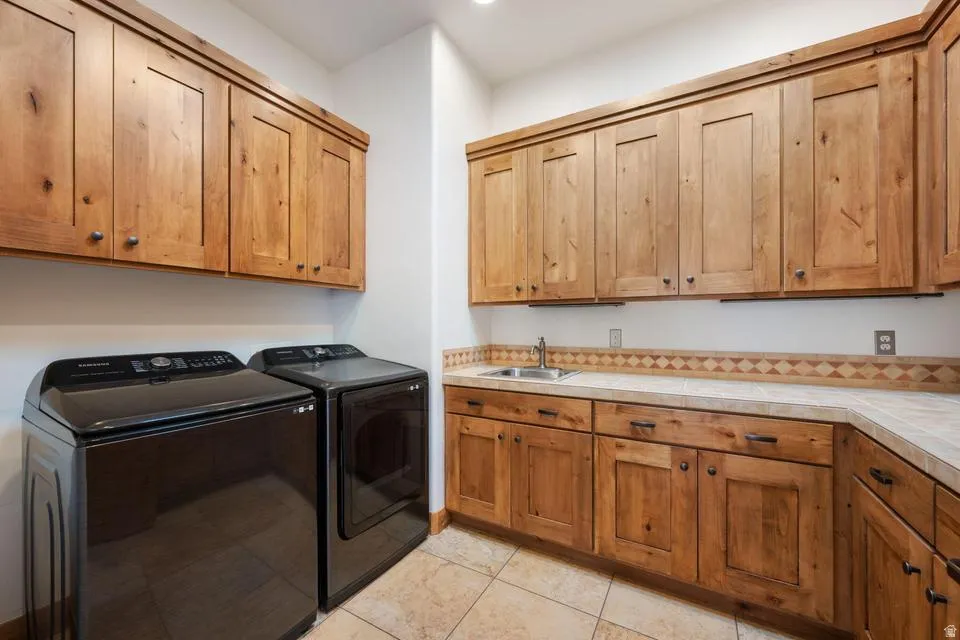 Laundry area with wood cabinetry, light-toned countertops, and a utility sink