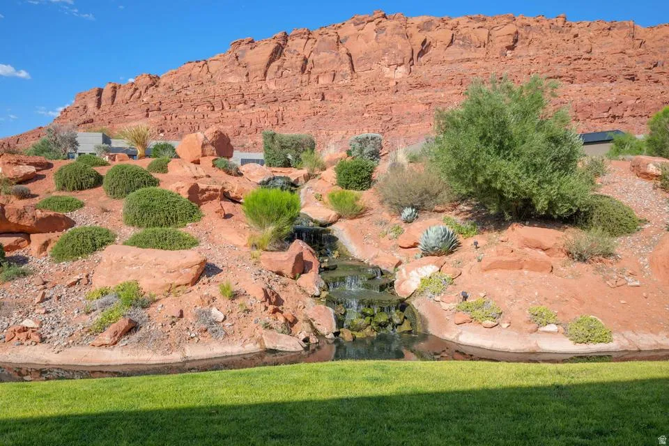 Expansive outdoor space featuring a rock formation, layered waterfall, and diverse desert landscaping