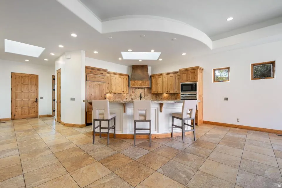 Spacious kitchen area featuring an island with counter seating, wood cabinetry, stainless steel appliances, and a tile backsplash
