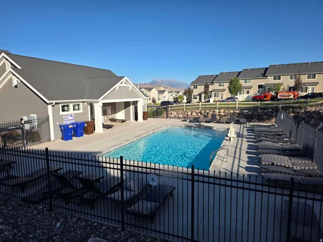 Outdoor swimming pool with integrated lounge areas and adjacent clubhouse featuring a covered patio