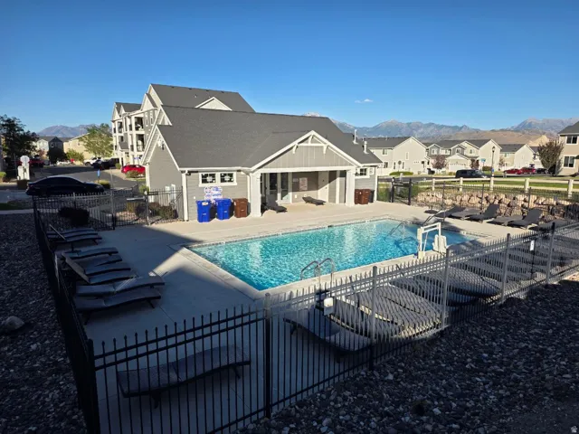 Pool area featuring a rectangular pool, concrete decking, and a surrounding black metal fence