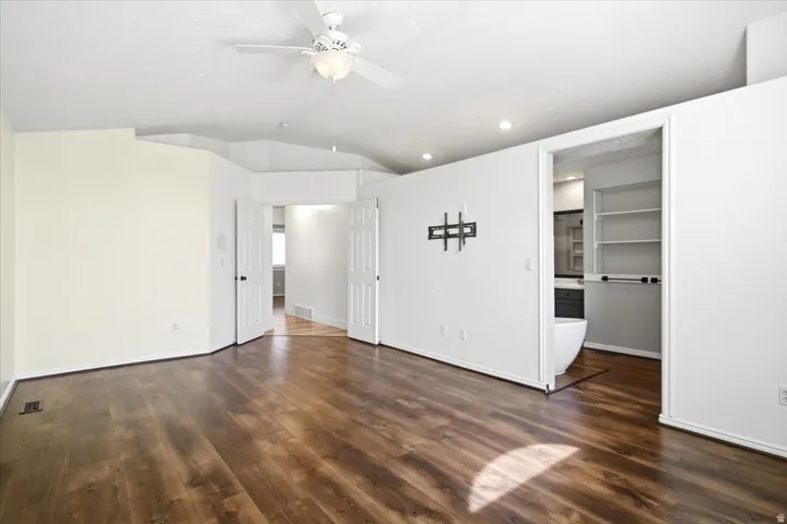 Wood-finish flooring throughout, vaulted ceiling, recessed lighting, and a ceiling fan