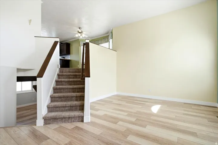 Wood-finish flooring, carpeted staircase with wood handrails, recessed lighting, ceiling fan