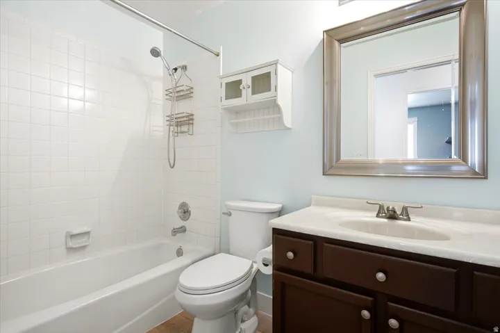 Bathroom featuring a white subway tile tub surround, white bathtub, dark wood-finish vanity with a white countertop, and a framed mirror
