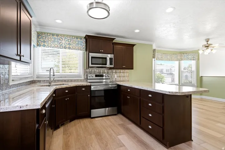 Dark wood-finish cabinetry, light-toned countertops, stainless steel appliances, and wood-finish flooring