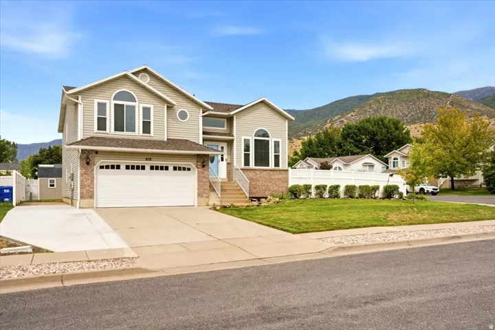 Two-story residence with a two-car garage, brick and siding exterior, arched windows, and a mountain backdrop