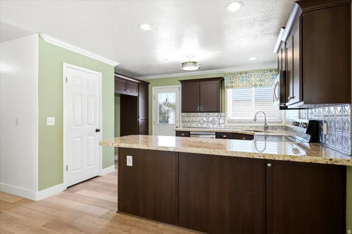 Kitchen featuring wood-finish flooring, recessed lighting, dark wood cabinetry, and light-toned countertops