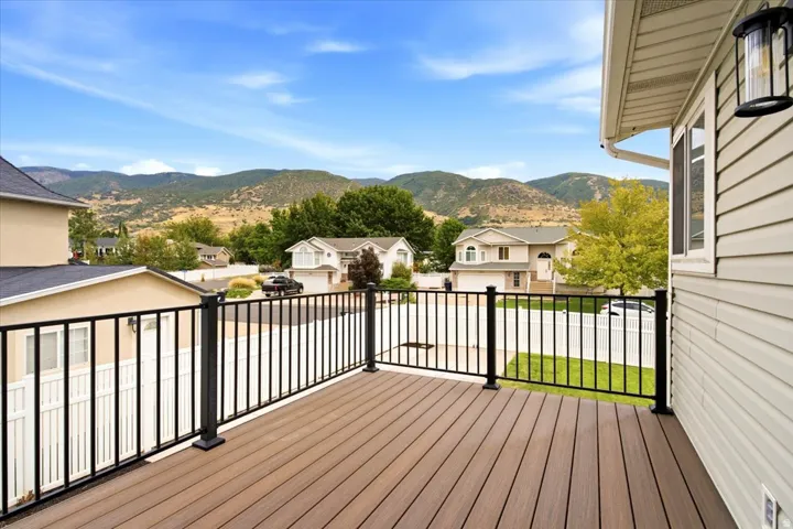 Composite deck with warm wood-finish flooring and black aluminum railing system overlooking manicured landscaping and mountain backdrop