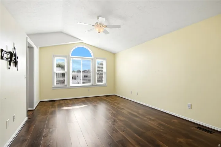 Vaulted ceiling, wood-finish flooring, ceiling fan, arched transom window, white window blinds