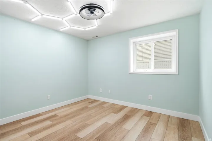 Wood-finish flooring, white trim, and a window with blinds