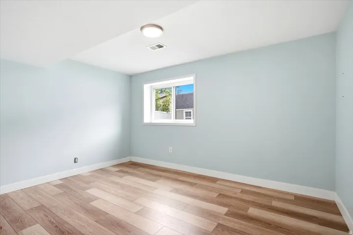 Light wood-finish flooring, white trim, and a window with a white frame