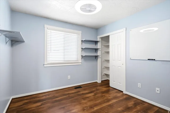 Wood-finish flooring, built-in shelving, white trim, and a ceiling-mounted light fixture