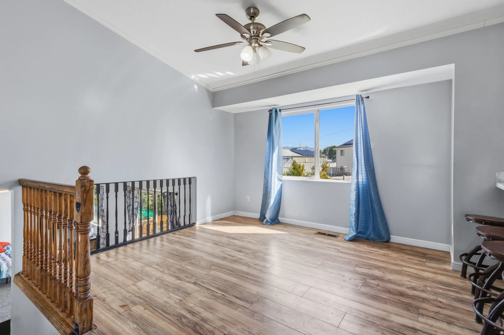 Spacious room featuring wood-finish flooring, a contemporary ceiling fan, and a large window with ample natural light
