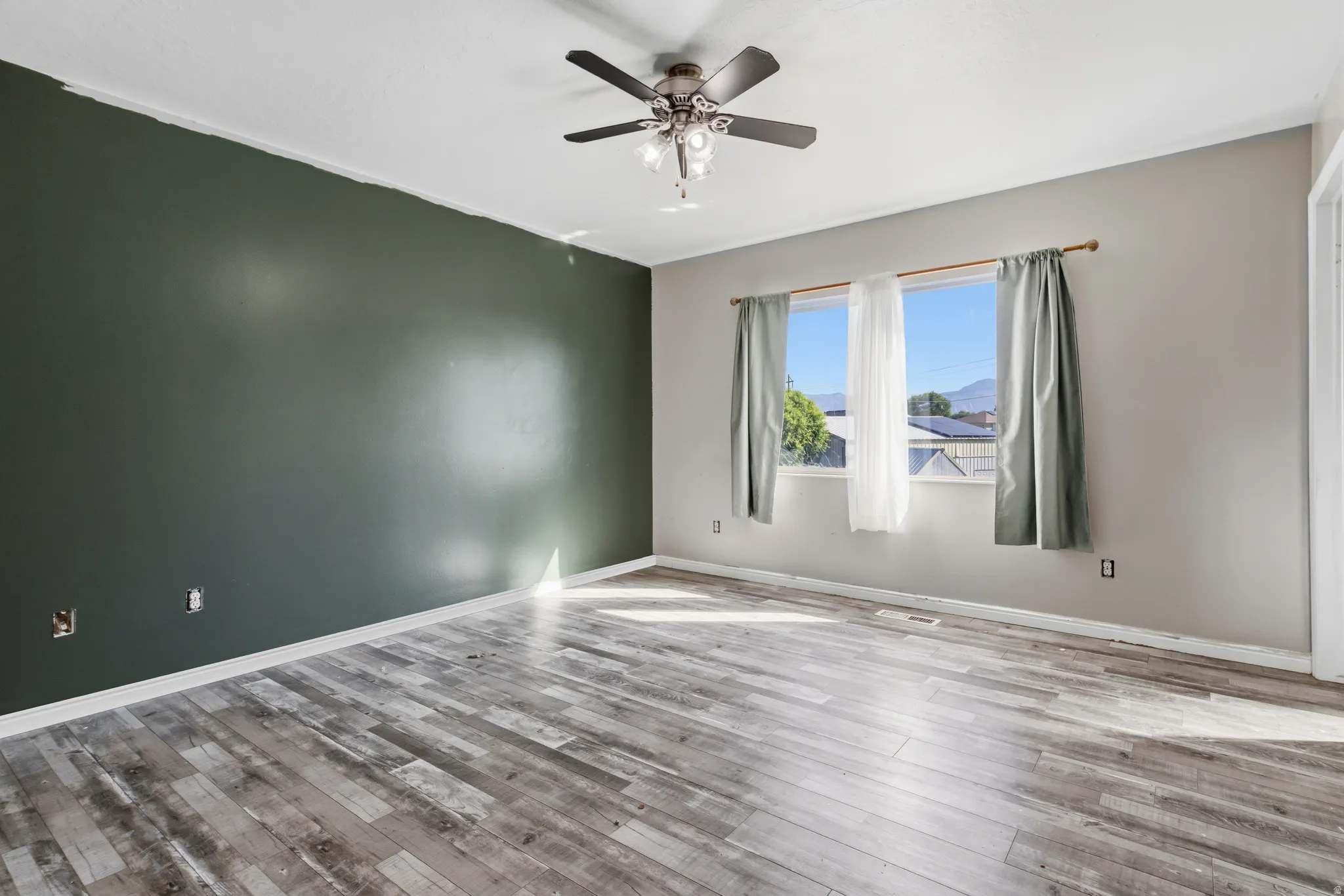Wood-finish flooring, ceiling fan, and window with natural light