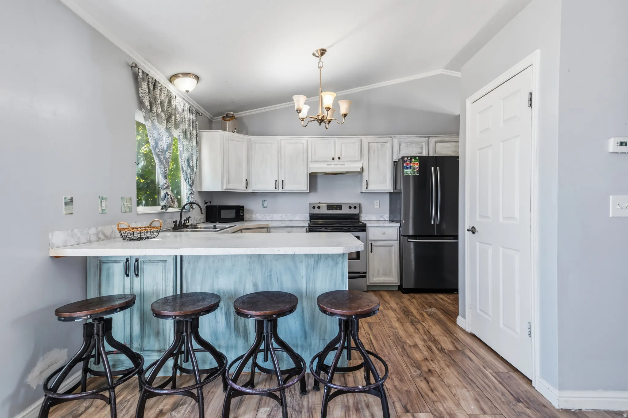 Kitchen featuring white cabinetry, wood-finish flooring, a white countertop, and a black refrigerator