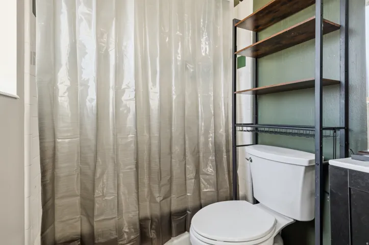 White toilet with a built-in over-the-toilet shelving unit featuring wood-finish shelves and a metal frame