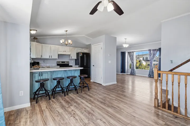 Open-concept living space featuring wood-finish flooring, a kitchen island with seating, a vaulted ceiling, and recessed lighting