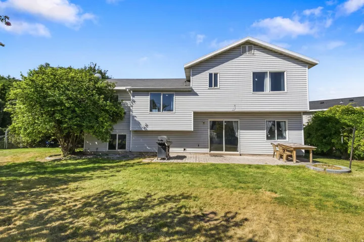 Expansive backyard with a manicured lawn, mature trees, and a paver patio