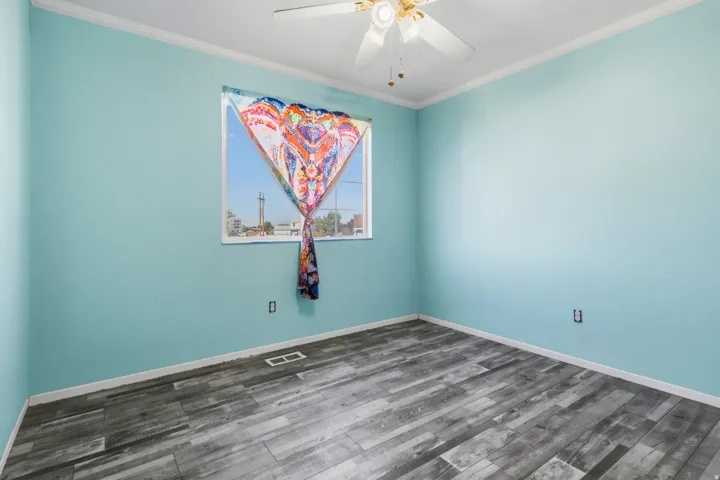 Wood-finish flooring, a window with natural light, and a ceiling fan with integrated lighting