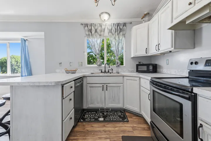 U-shaped kitchen featuring white cabinetry, light-toned countertops, and wood-finish flooring