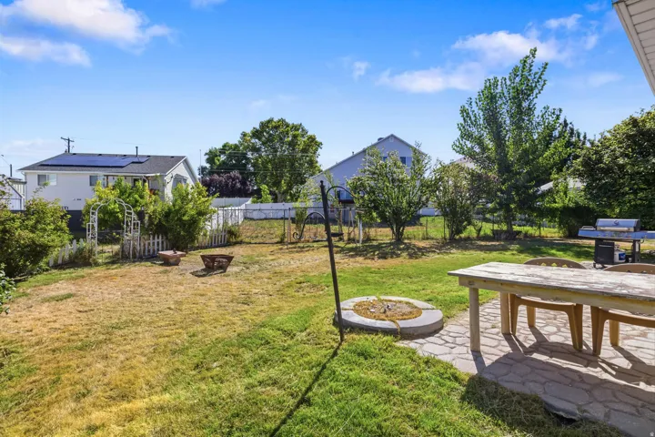 Expansive outdoor area featuring a stone patio, mature trees, and a fire pit