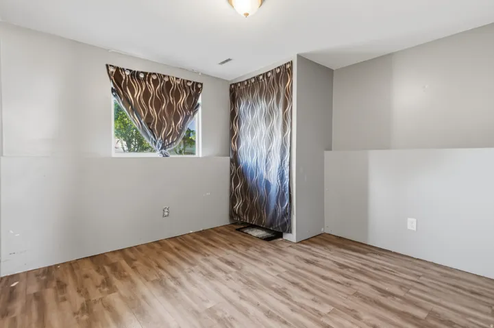 Wood-finish flooring with painted walls, featuring a window and overhead lighting