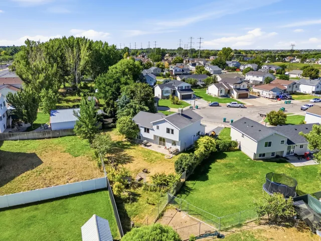 Two-story property featuring a light-colored exterior, a rear patio, and a spacious backyard with established landscaping