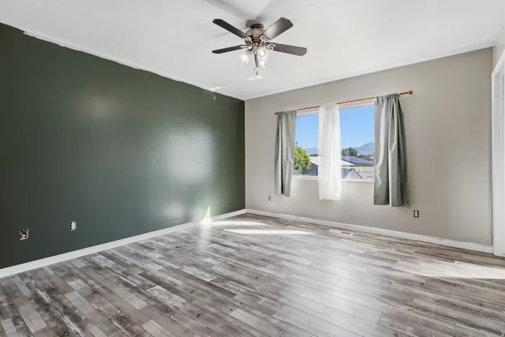 Wood-finish flooring, ceiling fan, and window with natural light