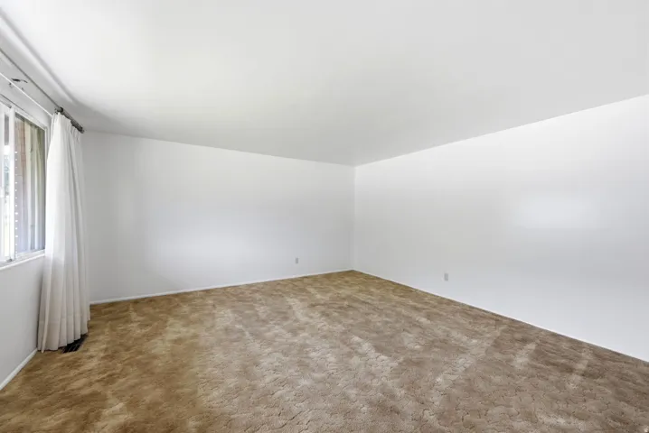 Spacious front living room with neutral carpeting and bright white walls