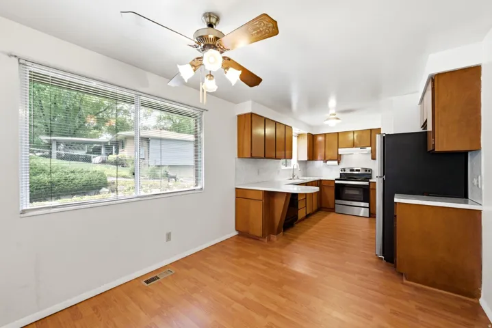 Main level kitchen featuring vinyl (LVP) flooring, wood cabinetry, and a ceiling fan with integrated lighting