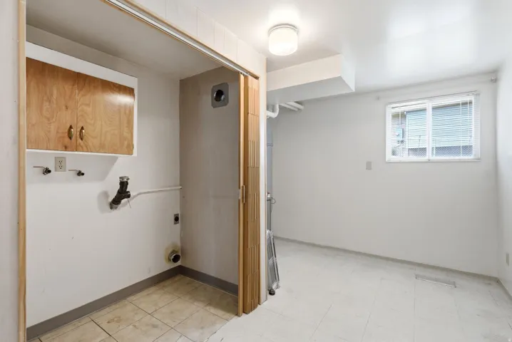 Basement laundry, furnace, and storage areas with wood cabinetry, vinyl tile flooring, and overhead lighting