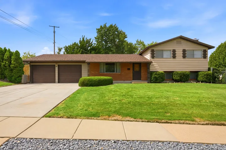 Front of home exterior with two-car garage, brick facade, mature landscaping, and a concrete driveway