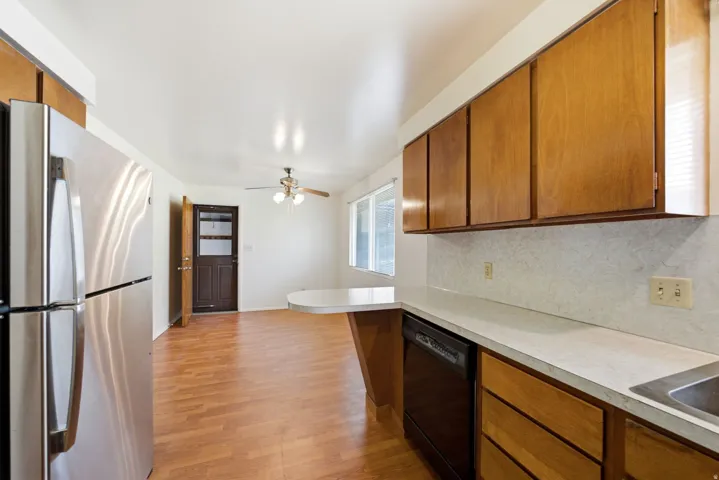 Main level Kitchen with vinyl (LVP) flooring, complemented by a stainless steel refrigerator, built-in dishwasher, and wood cabinetry