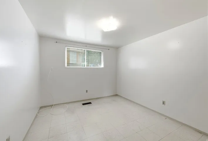 Basement bedroom with white walls, vinyl tiled flooring, window, closet, and overhead lighting